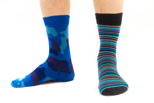 Man’s feet in colorful mismatched socks. White background with copy space.