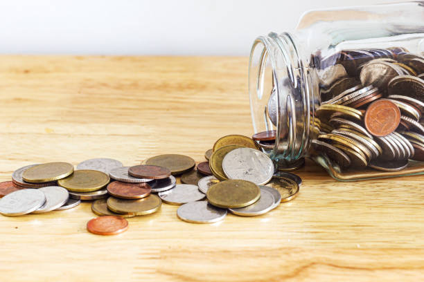 istock Silver and gold coin pour from grass jar bottle on wood table with white background 843087044