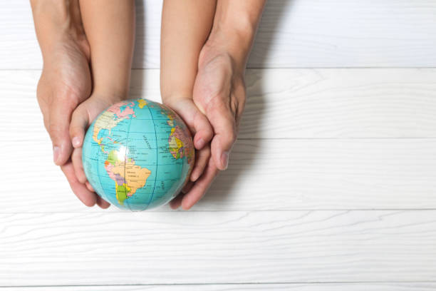 istock World concept: Two human hands holding global on wooden background. 843092784
