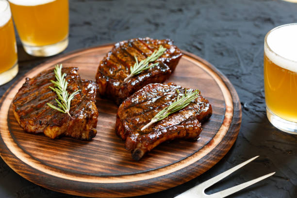 Very delicious steak BBQ and beer in glasses on a black stone background stock photo