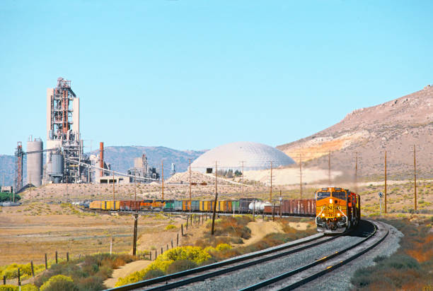 грузовой поезд bnsf проходит мимо промышленного цементного завода в калифорнии - tehachapi стоковые фото и изображения