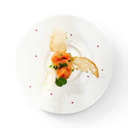 Salmon with caviar and avocado on a creamy substrate sprinkled with fresh herbs in white bowl on isolated background. Menu of gastronomic restaurant