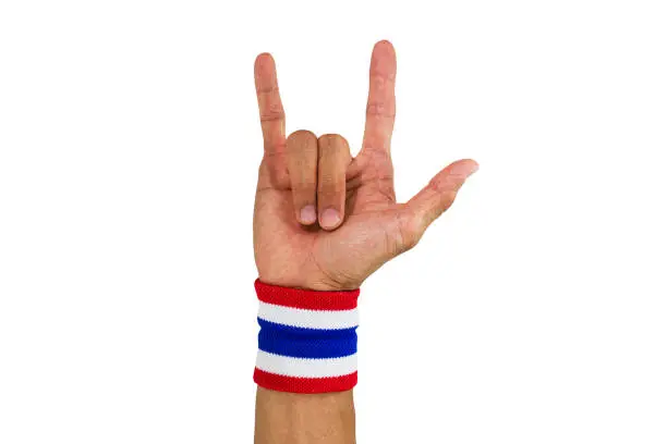 Photo of Thai national color cloth wristband on the guy's wrist making I love you sign on white background