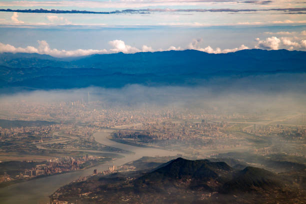 The city of Taipei, the capital of Taiwan, seen from an airplane during the afternoon. Some fog hanging over the city.