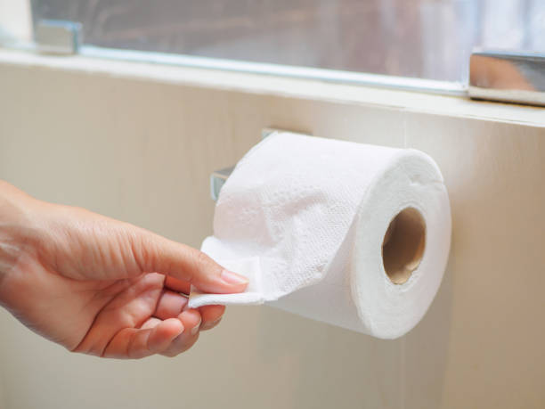 istock Closeup female hand picking a white tissue from tissue roll in the restroom. 843123058