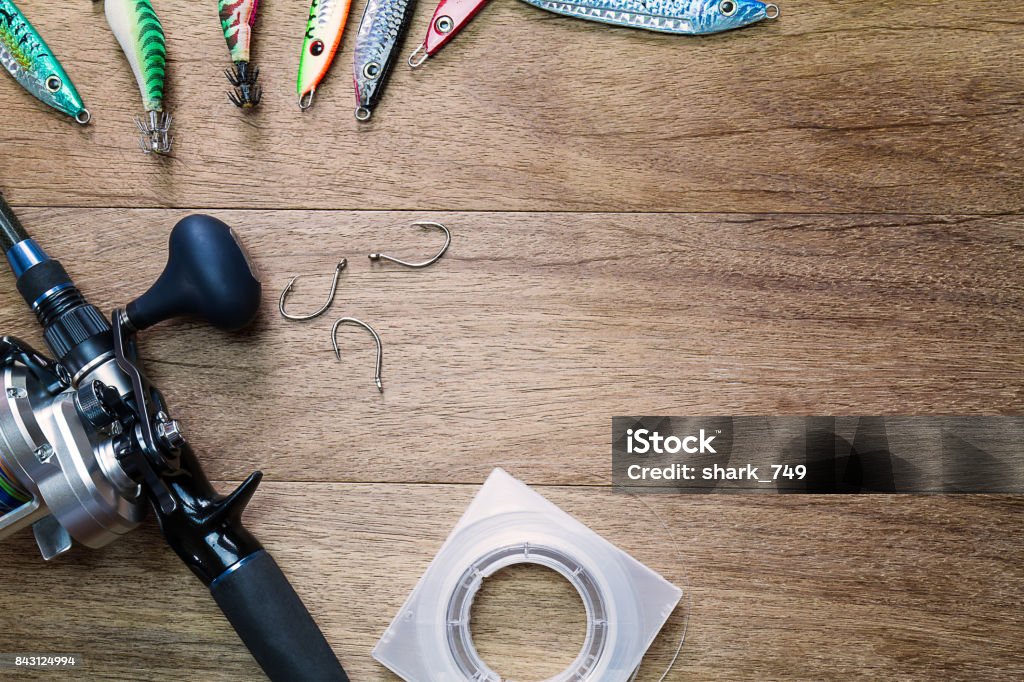 Fishing rod, lures,hooks,reel and string on vintage grunge wooden background, fishing hobby concept Artificial Stock Photo