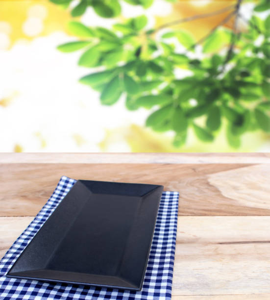 istock black dish on checkered tablecloth and blur leaves background 843127572