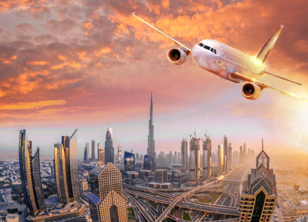 Airplane is flying over Dubai against colorful sunset in United Arab Emirates Airplane is flying over Dubai against colorful sunset in United Arab Emirates khalifa stock pictures, royalty-free photos & images