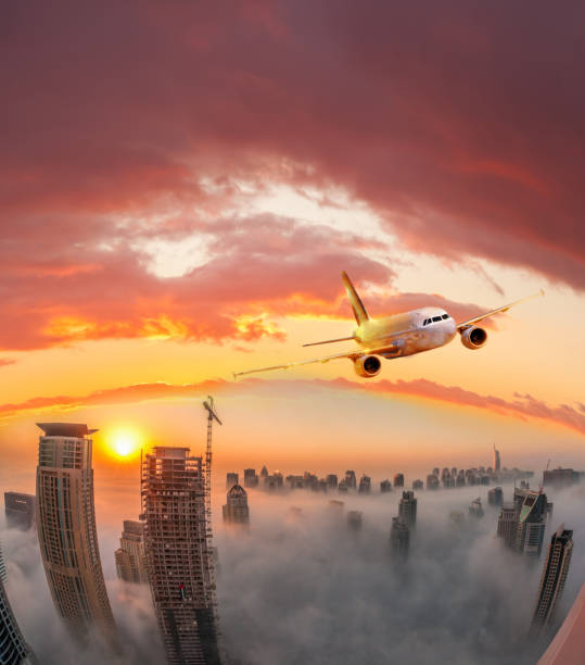 Plane is flying over Dubai against colorful sunset in United Arab Emirates Plane is flying over Dubai against colorful sunset in United Arab Emirates khalifa stock pictures, royalty-free photos & images