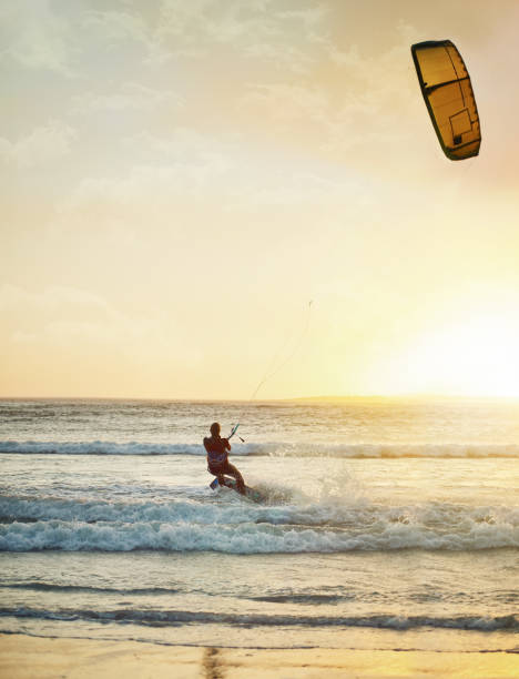 Rearview shot of a young woman kitesurfing at the beach