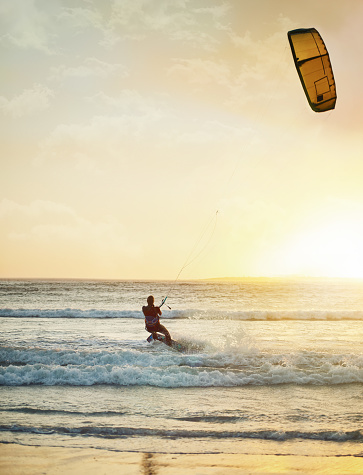 A young woman kitesurfer rides the waves doing a trick. Marine sports. kitesurfing.