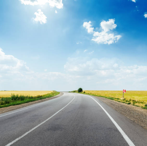 istock asphalt road in field and deep blue sky with clouds and sun 843143892