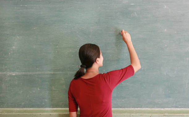 istock asian teacher writing on blackboard with chalk in classroom, Educations concept. 843154944