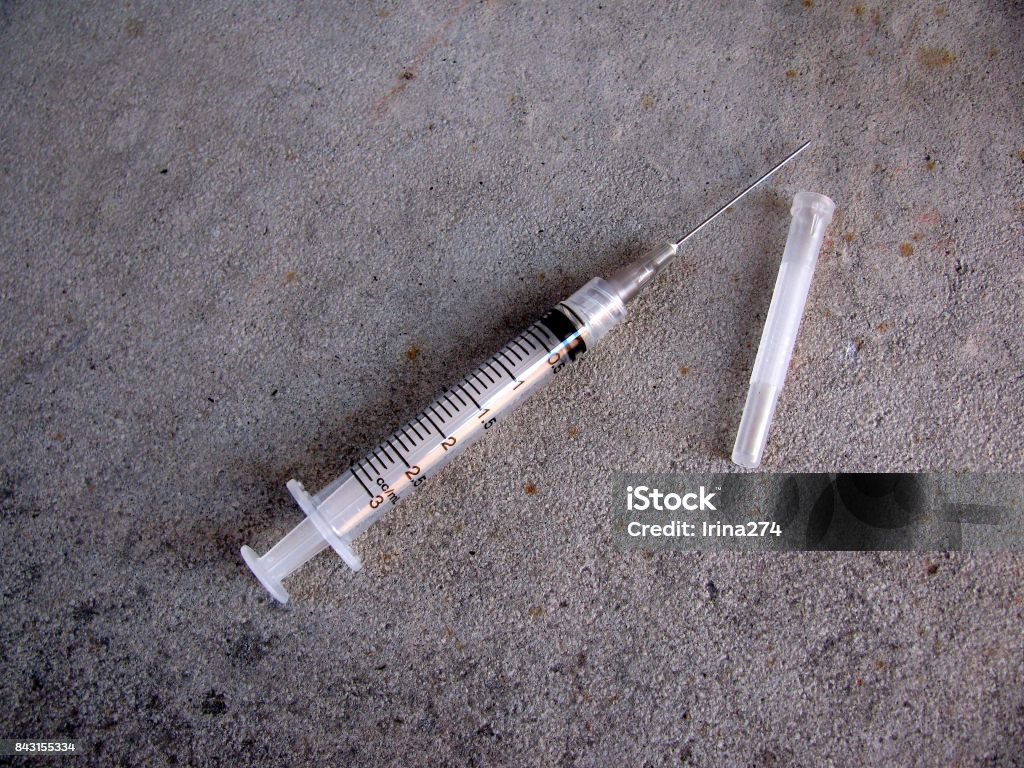 Syringe and needle on concrete floor Syringe Stock Photo