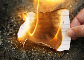 Female hand burns love letter: it's over.