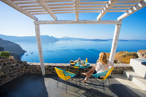 Woman enjoying breakfast with beautiful view over Santorini