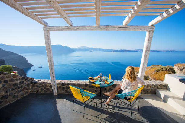 Woman enjoying breakfast with beautiful view over Santorini Woman enjoying breakfast with beautiful view over Santorini greece travel stock pictures, royalty-free photos & images