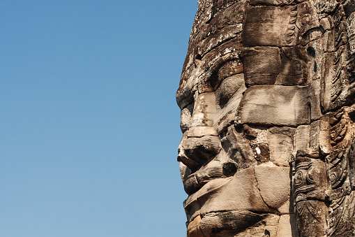 Ancient stone face of the Bayon temple in the jungle, Angkor, Cambodia