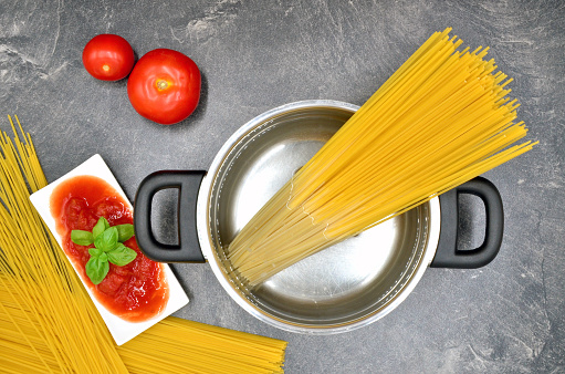 cooking spaghetti in pot with tomato close up