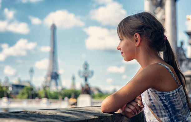 Little girl sightseeing Paris. The girl aged 9 is at the bank of river Seine, enjoying cityscape of Paris. \n