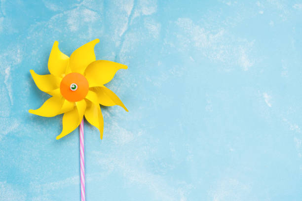 Colorful paper windmill toys on blue stone background. Summer concept. Copy space