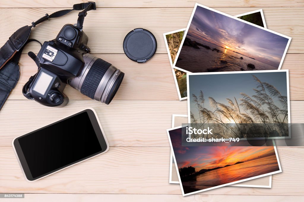 Old camera, smartphone and stack of photos on wooden background Smart Phone Stock Photo