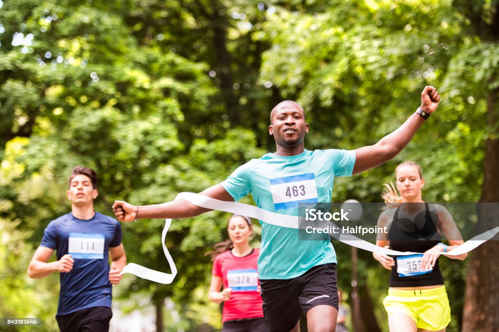 Young man running in the crowd crossing the finish line. African man running in the crowd crossing the finish line. Marathon Stock Photo