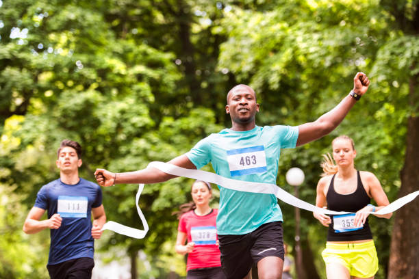 young man running in the crowd crossing the finish line. - finish line imagens e fotografias de stock