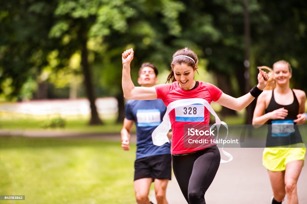 Junge Frau in der Menge, die über die Ziellinie laufen. - Lizenzfrei Marathon Stock-Foto