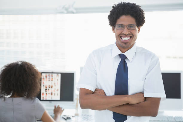 istock Young handsome editor smiling at camera with colleague working behind him 843189546