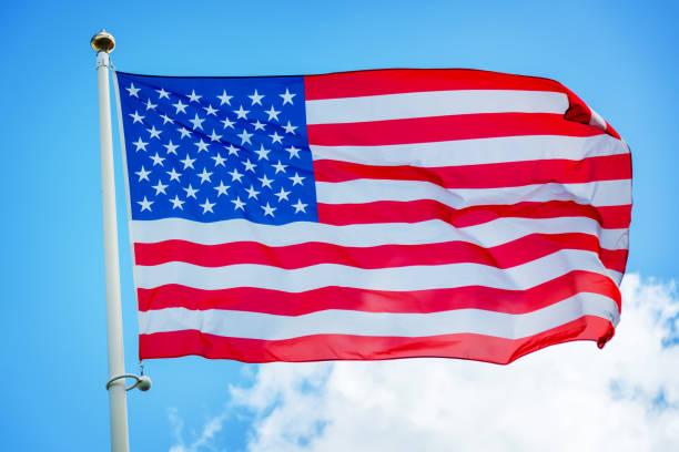 istock American US flag on a pole against blue sky 843193162