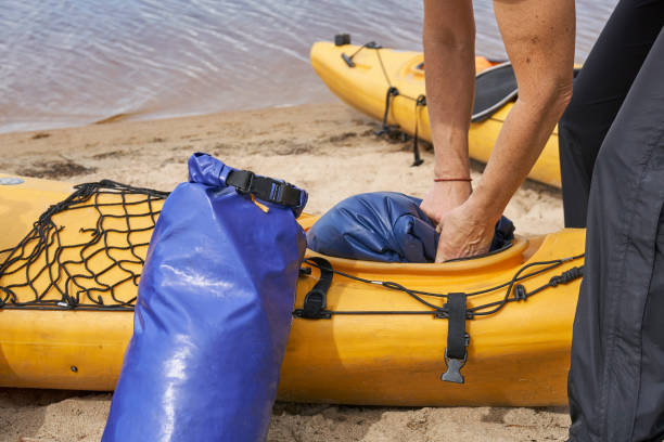 Female hiker puts a waterproof bag into the kayak stock photo