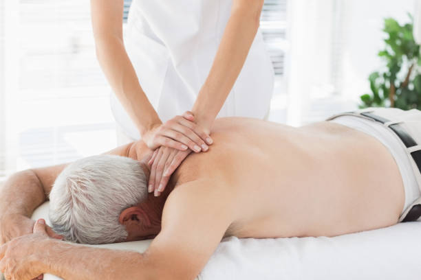 istock Therapist massaging back of senior patient 843208886