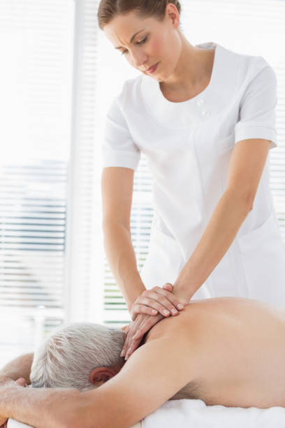istock Therapist massaging back of senior man 843208916