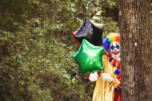 Creepy Clown Holding Balloons A creepy clown in the woods holding balloons. clown photos stock pictures, royalty-free photos & images