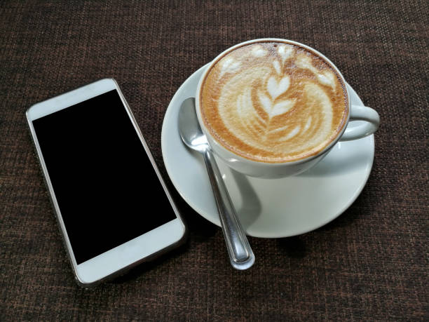 Shallow focus close up image of a cappuccino and a smartphone on the table in the cafe in Kreuzberg.