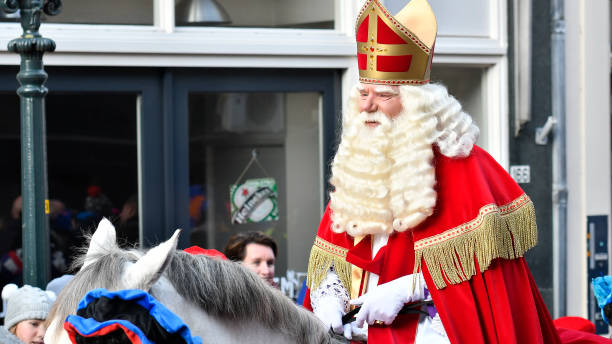 Sinterklaas arriving in the city of Kampen for the Sint Nicolaas festival Arrival of Sinterklaas in the city of Kampen. The old Saint is riding his horse through the crowded shopping street surrounded by his helpers the Black Petes. Sinterklaas is a traditional Dutch holiday for children that is celebrated on the 5th of December. In recent year there is a strong discussion about the role of Zwarte Piet in this culutural tradition. zwarte piet stock pictures, royalty-free photos & images