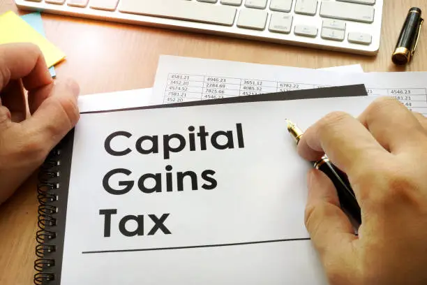 Photo of Hands holding documents with title capital gains tax CGT.