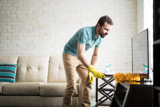 Young man cleaning with a duster Attractive Latin man in his 30s doing house chores to maintain his apartment clean dusting stock pictures, royalty-free photos & images