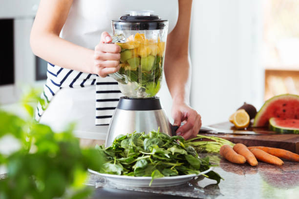 Vegetarian preparing vegan smoothie Vegetarian preparing vegan smoothie with rucola, citrus, cucumber in kitchen with carrots on countertop arugula photos stock pictures, royalty-free photos & images