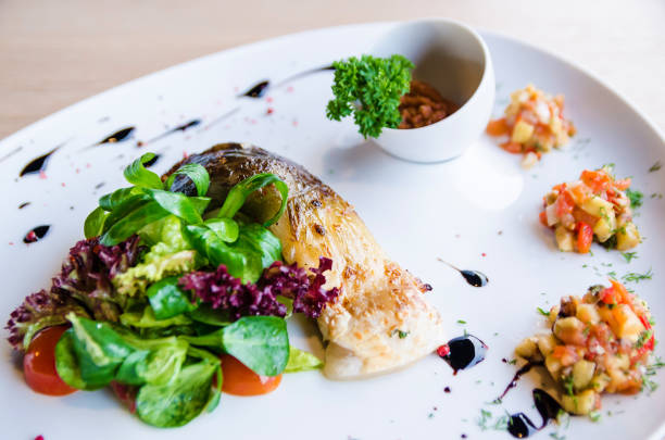 Appetizing Grilled fish with tomato and lettuce on brown table