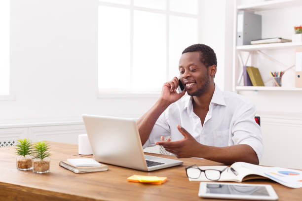 istock Young black businessman talking on mobile in modern white office 843276658