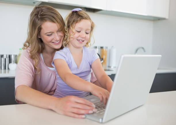 istock Mother assisting daughter in using laptop at table 843276866