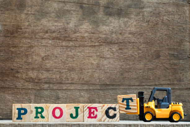 istock Toy plastic forklift hold block T to compose and fulfill wording project on wood background 843281492