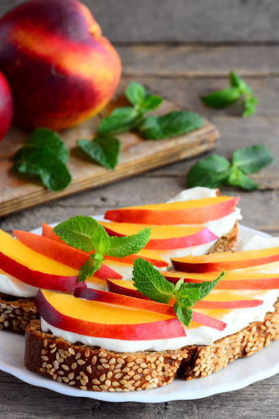 istock Light sandwiches with cream cheese, nectarines and mint on a serving plate and on a vintage wooden table. Healthy sandwich recipe for kids. Vertical photo 843281712