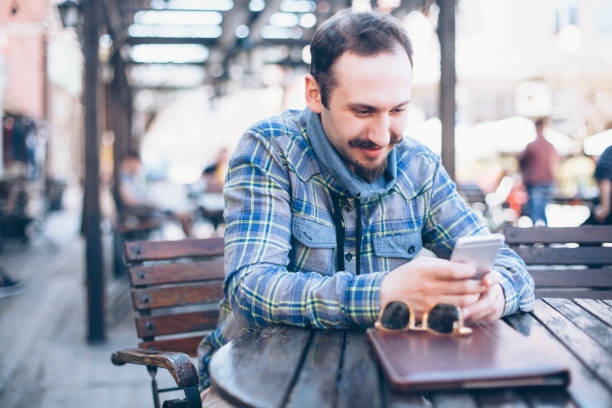 istock Man sitting at sidewalk cafe and using smart phone 843289556