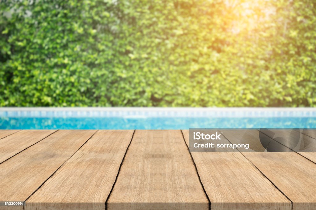 Empty wooden table in front with blurred background of swimming pool Swimming Pool Stock Photo
