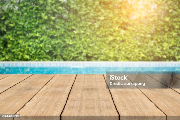 Empty Wooden Table In Front With Blurred Background Of Swimming Pool Stock Photo - Download Image Now