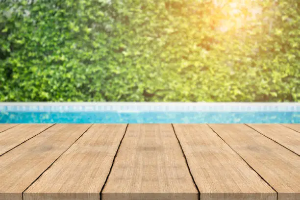 Photo of Empty wooden table in front with blurred background of swimming pool