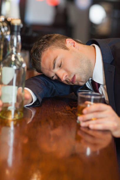 istock Drunk businessman holding whiskey glass lying on a counter 843305842